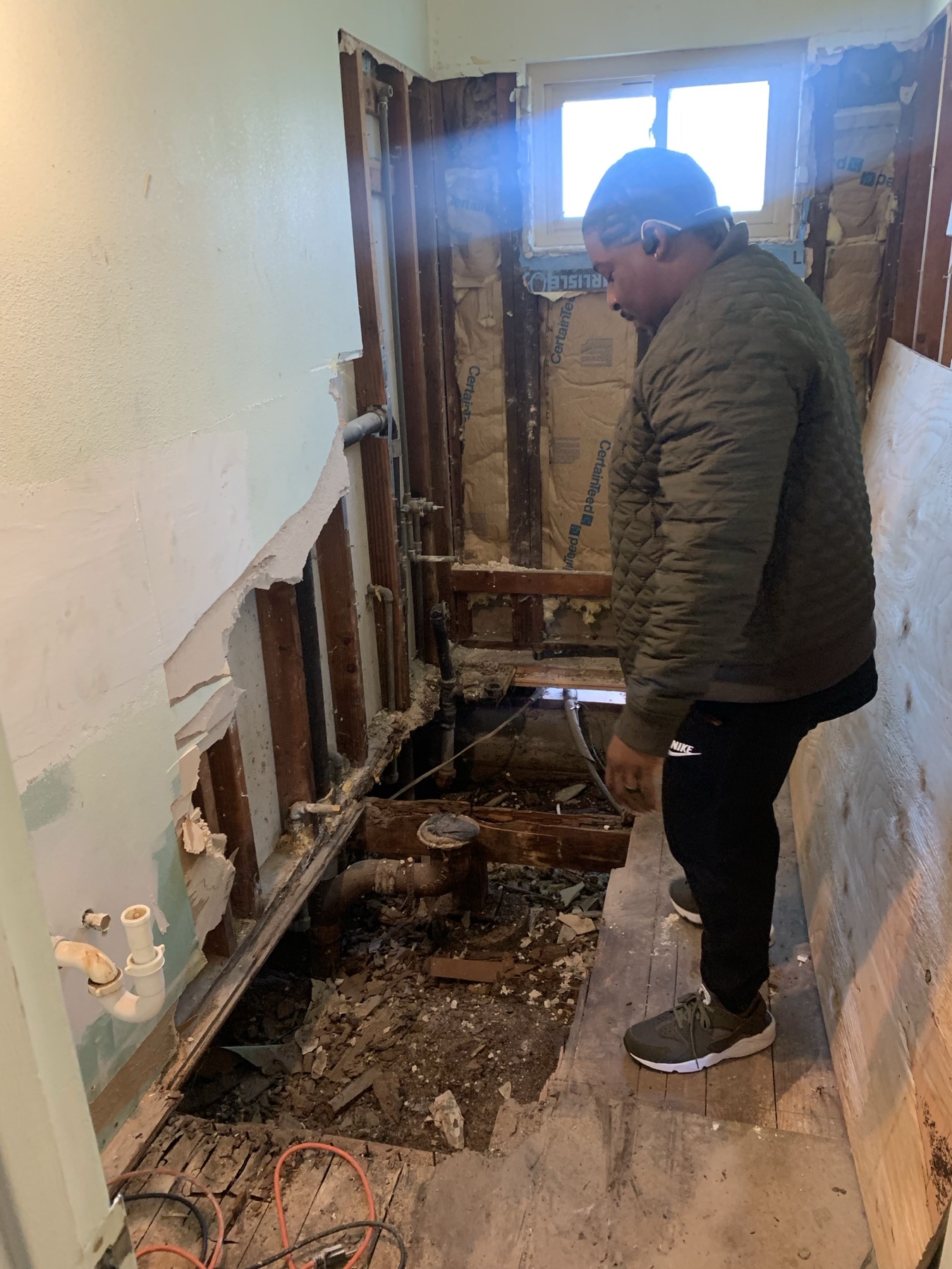 Bathroom taken down to the studs during demolition, with the old floor removed