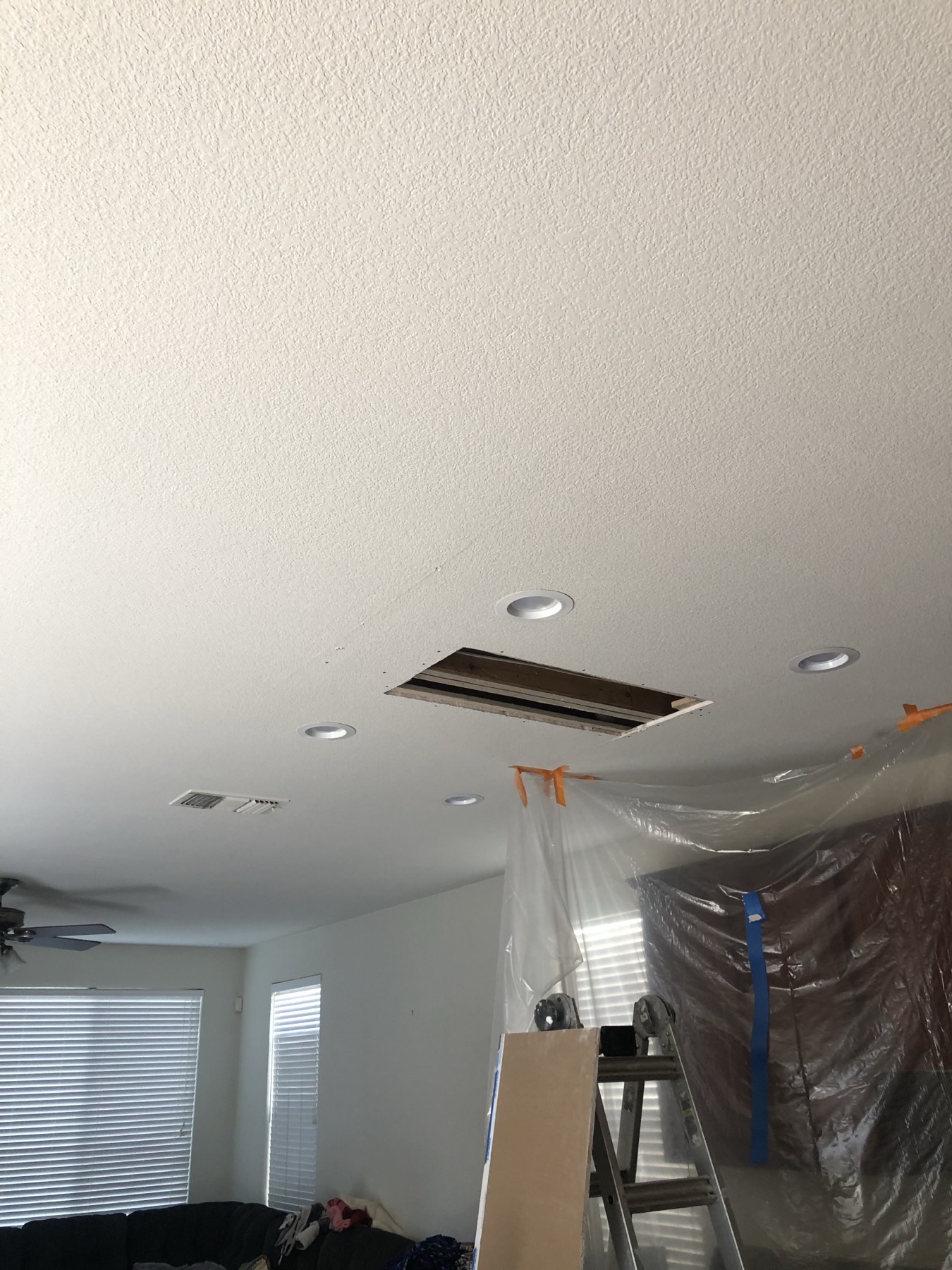 Kitchen ceiling with a rectangular opening and the room protected by plastic sheeting